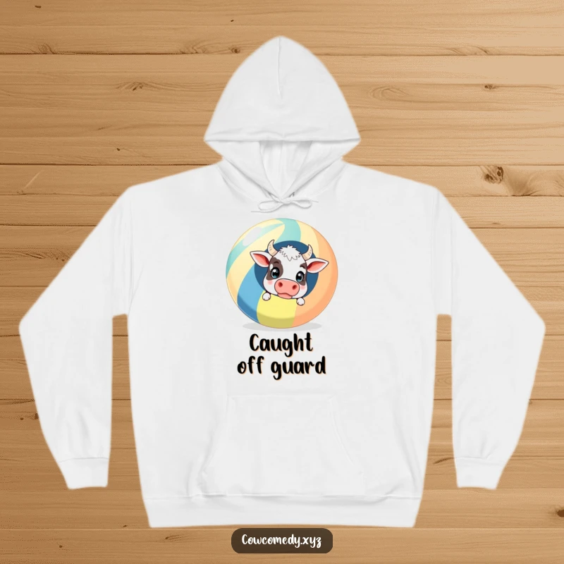 Funny Hoodie: A surprised cow peeking out from behind a giant striped beach ball, offering cozy comfort with a humorous beach theme.